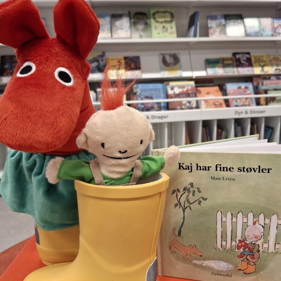 Foto af en dukke og Kaj-bogen