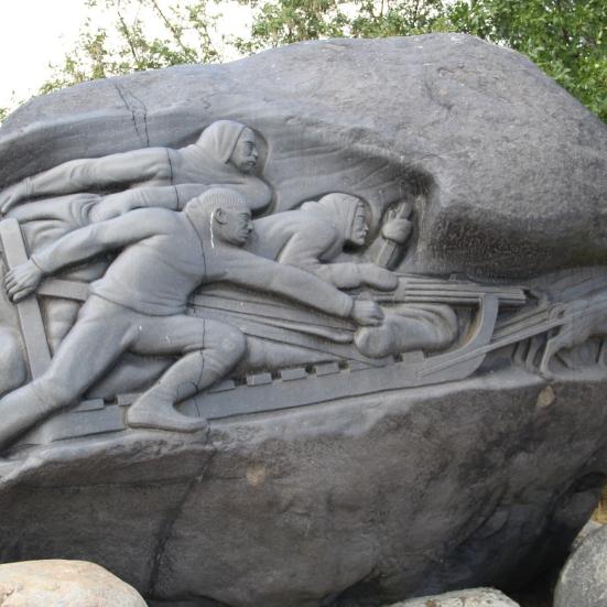 Relief på Langeliniemonumentet af slædeholdet, der viser deltagerne og hundene.