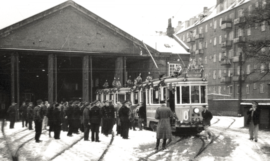 En flok medarbejdere beskuere en julepyntet sporvogn